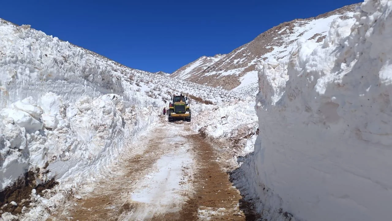 Maquinaria QMT circulando por un camino despejado entre altos bancos de nieve