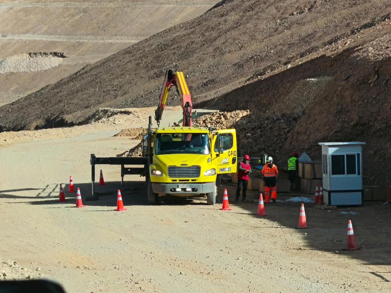 Camión pluma QMT y equipo trabajando en terreno